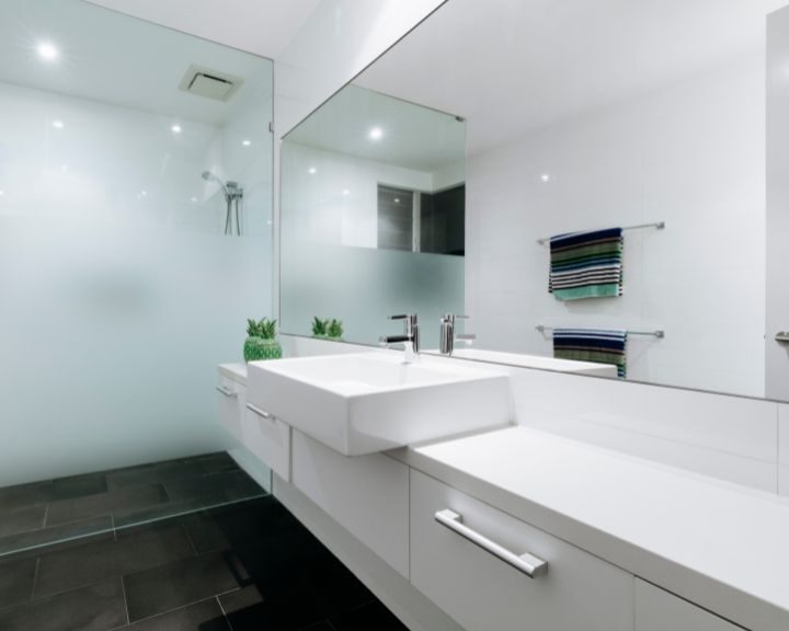A sleek bathroom with a large mirror and a sink, featuring City-inspired cabinets.