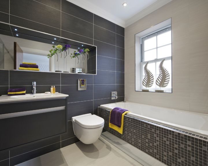 A white toilet and bathtub under a window in a bathroom remodel in the city.